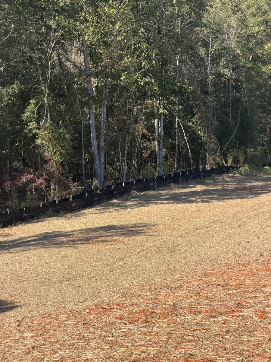 Silt fence along the tree line below a strawed grade