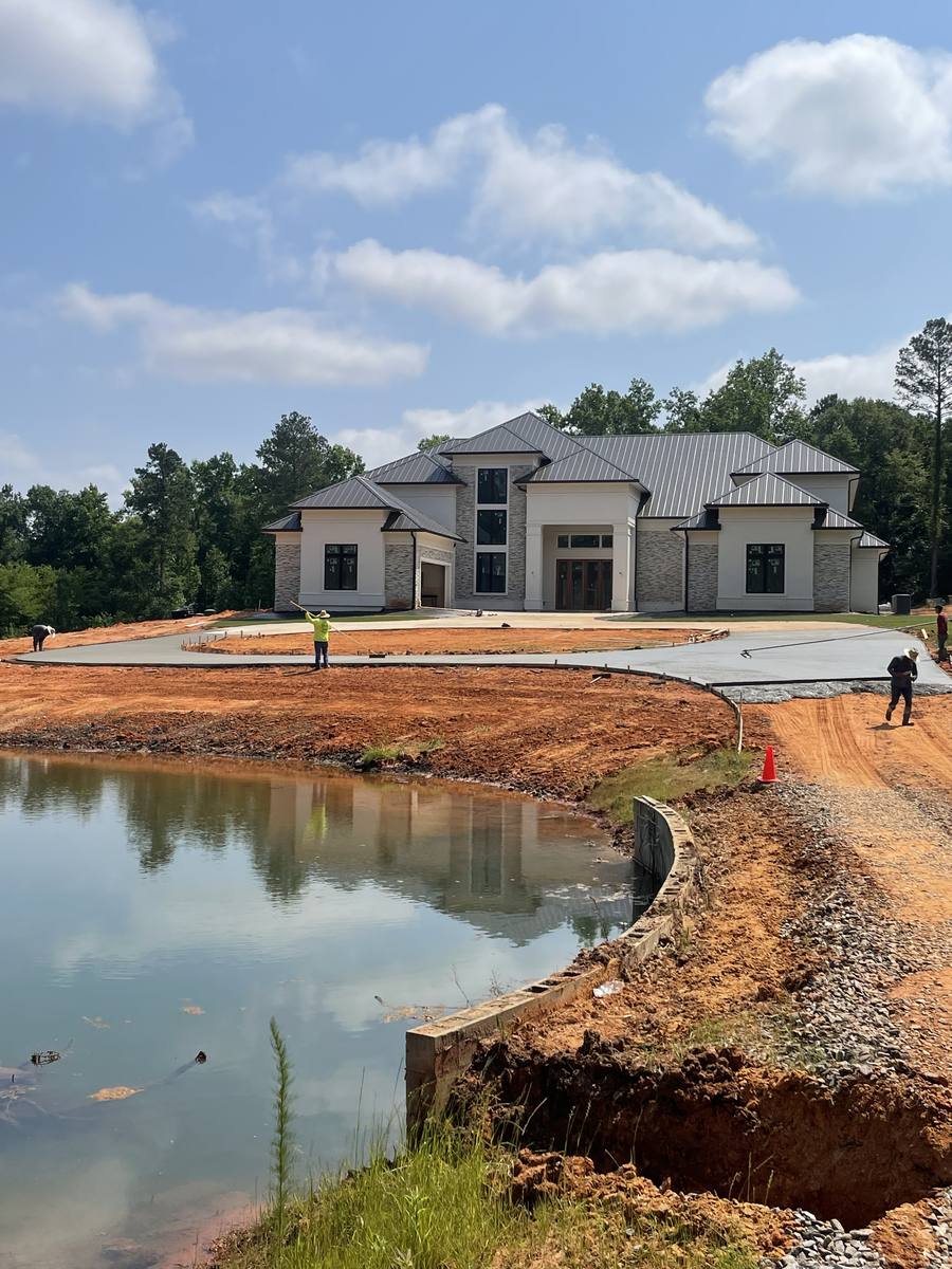 Crew grading around a pond and drive at a large custom home